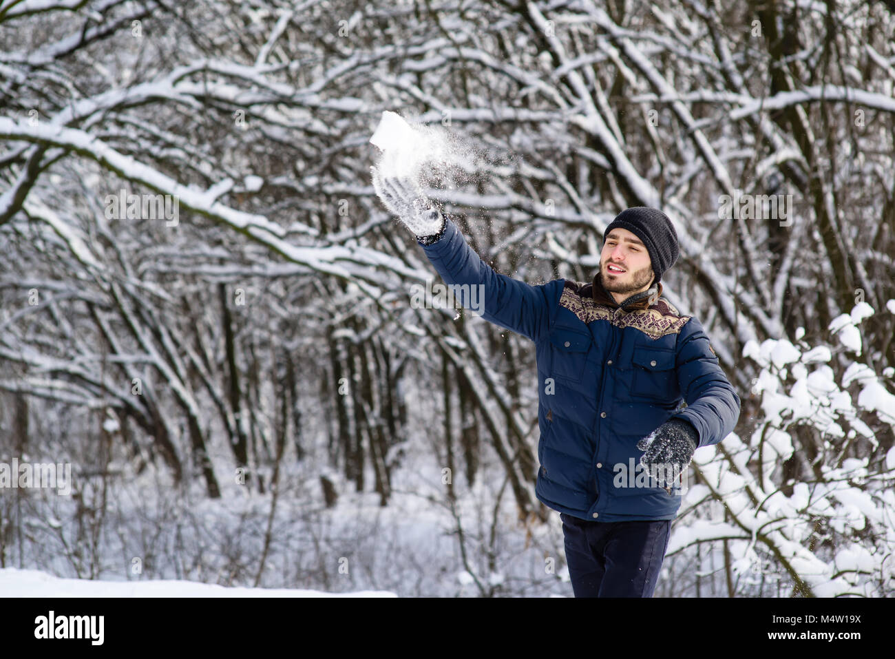 Happy young man with beard throw snowball Stock Photo