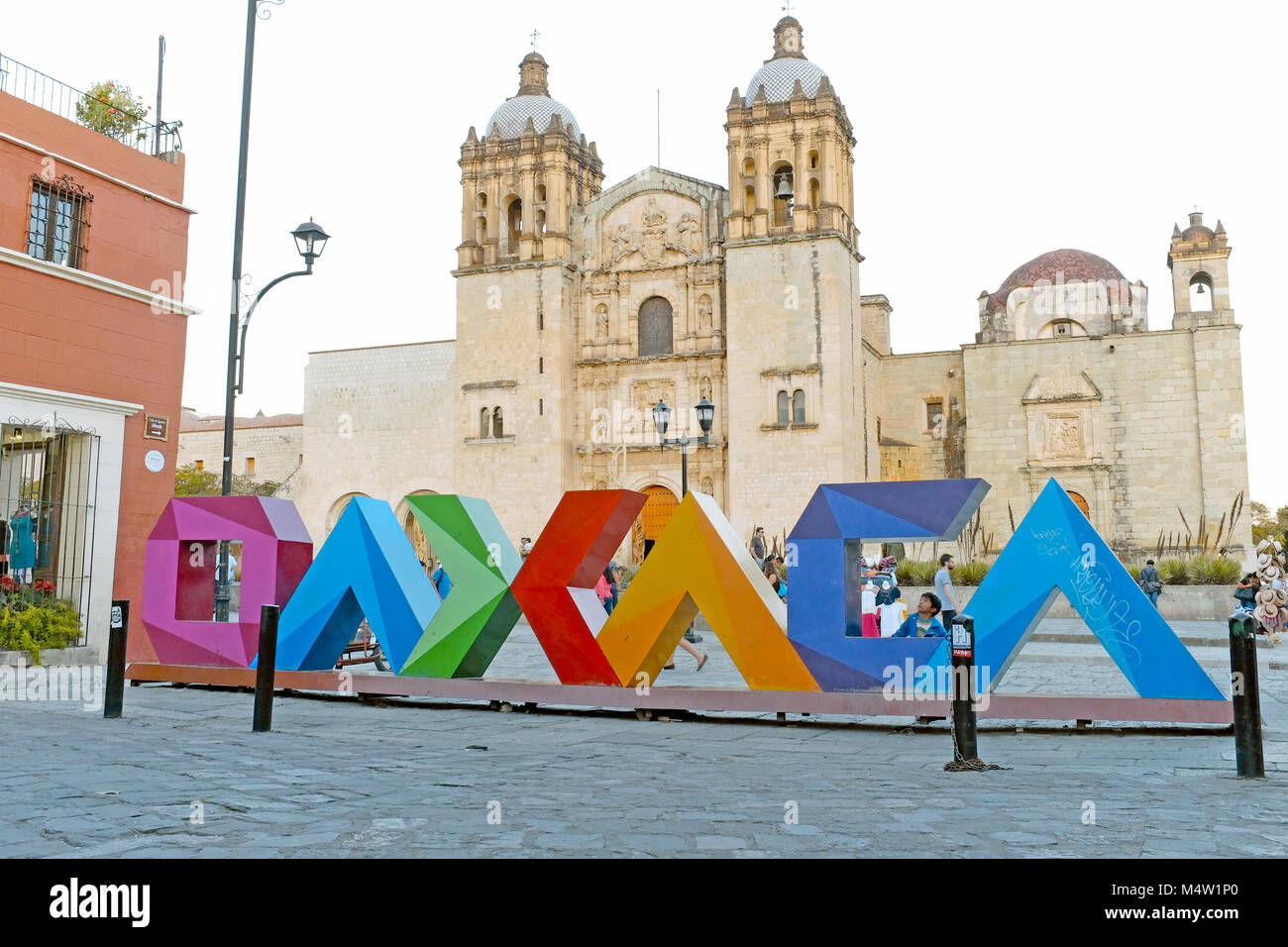 Colorful Oaxaca letters contrast with the iconic landmark Templo de Santo Domingo de Guzman in Oaxaca, Mexico. Stock Photo