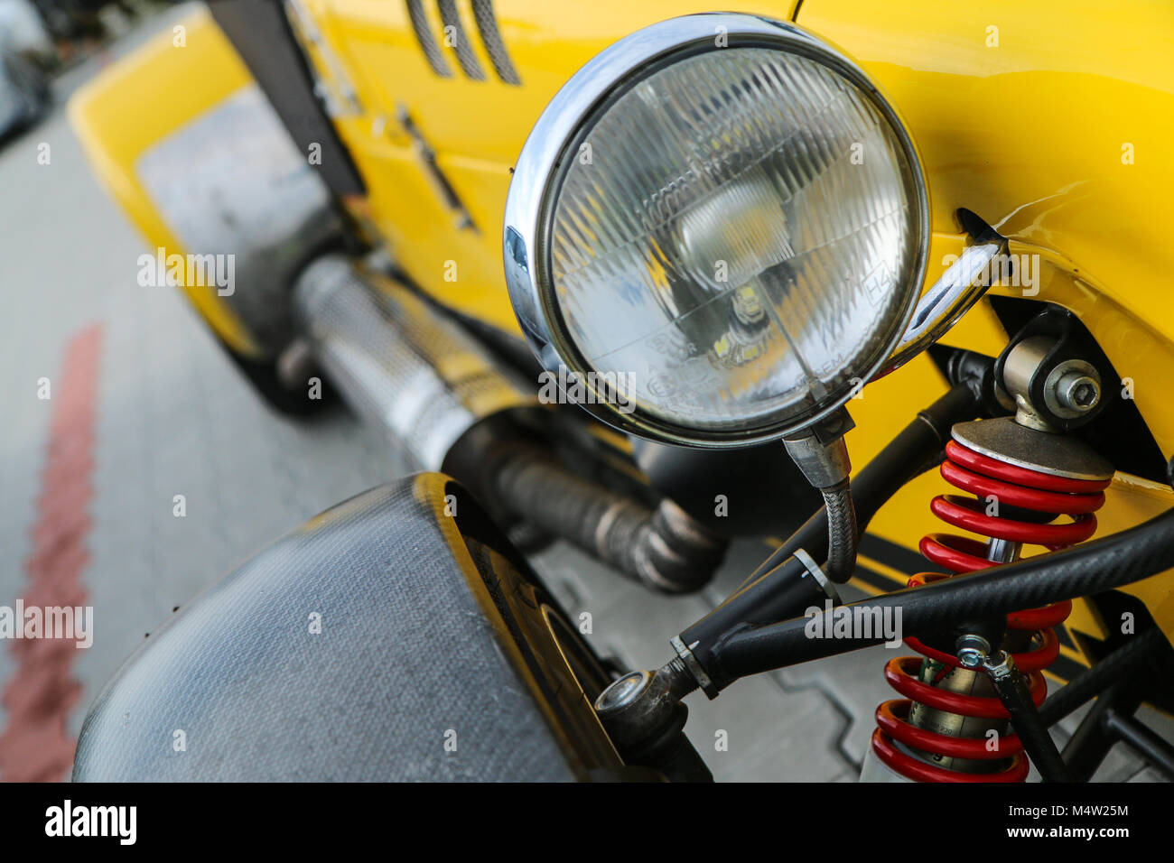 A detail of a light sport car´s headlight and suspension. The bodywork is visible with the side exhaust. Stock Photo