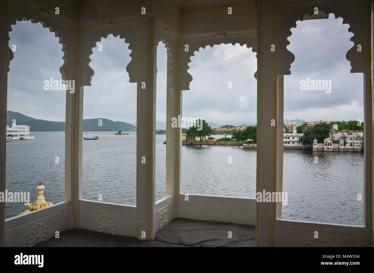 Lake Pichola and City Palace seen through 4-panel, scalloped Indian windows in Udaipur, India. Stock Photo