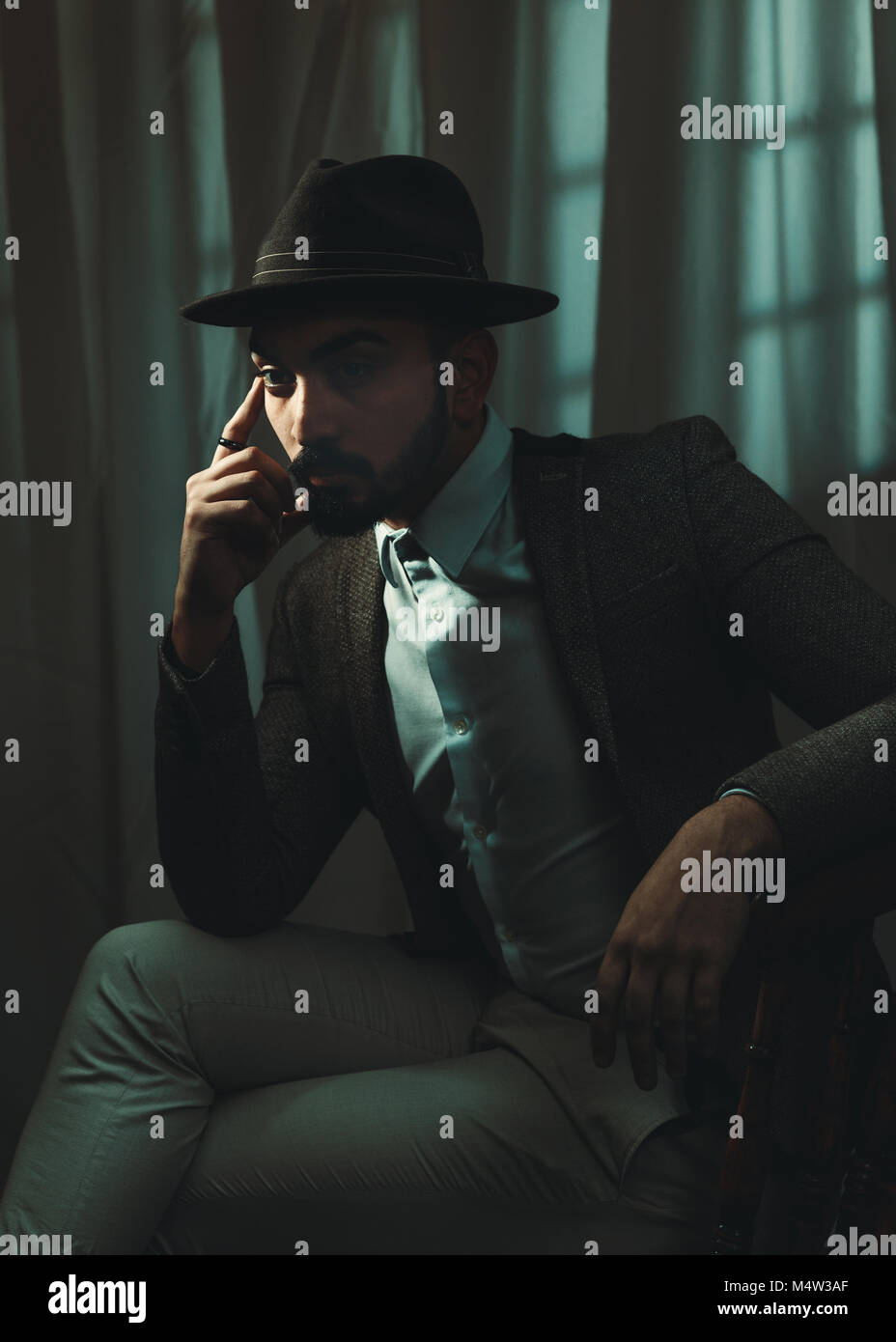 Film Noir style image with cinematic tone of man wearing a trilby hat Stock Photo