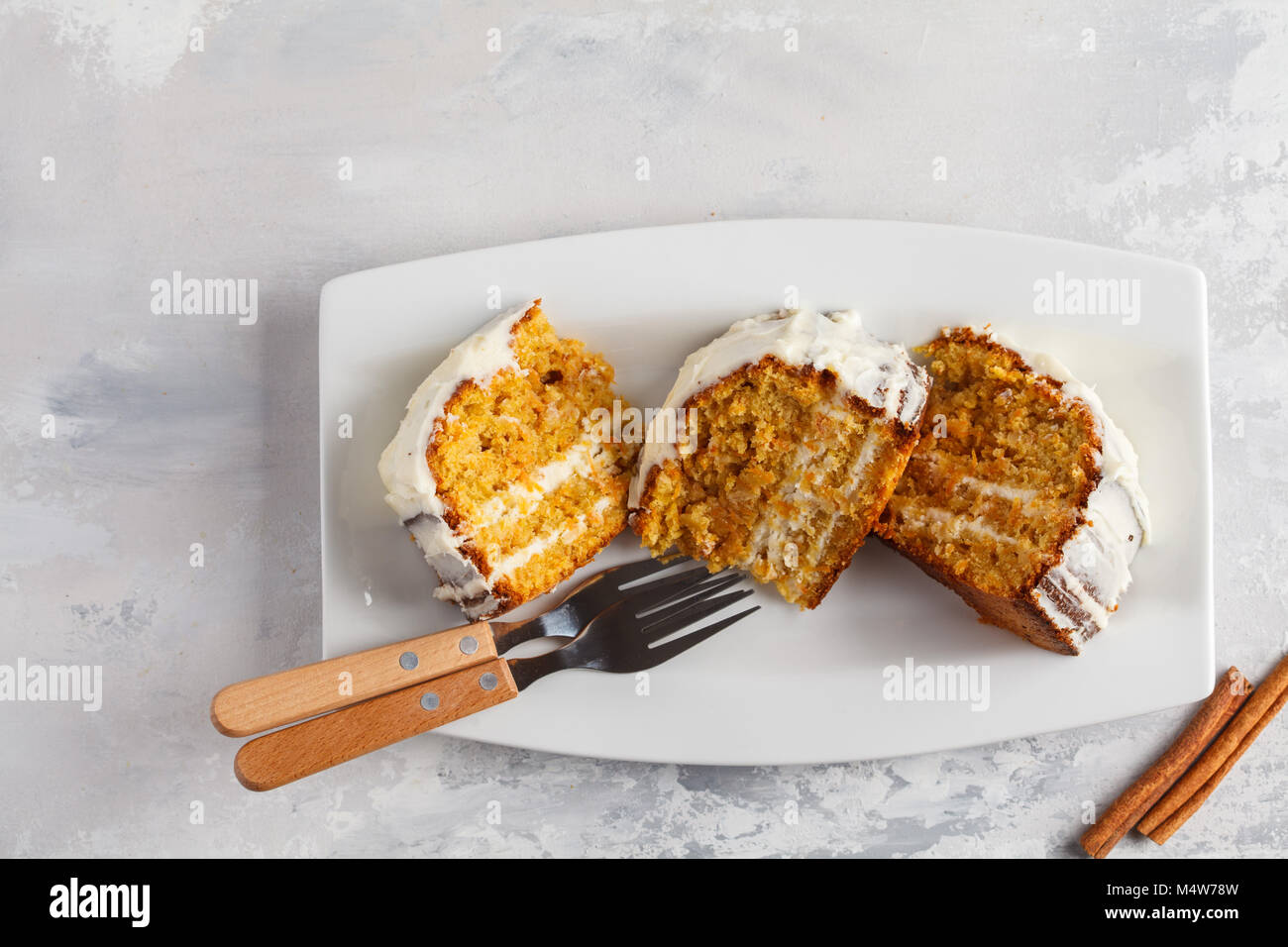 Pieces of homemade carrot cake with white cream on white dish. Festive dessert concept. Stock Photo