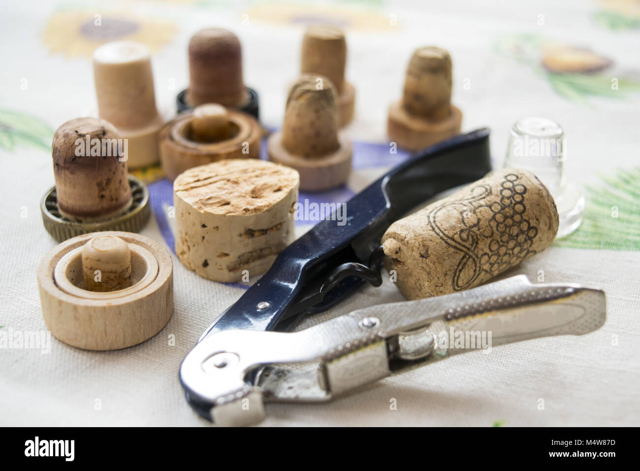 corkscrew with inserted wine cork and series of stoppers on the background Stock Photo