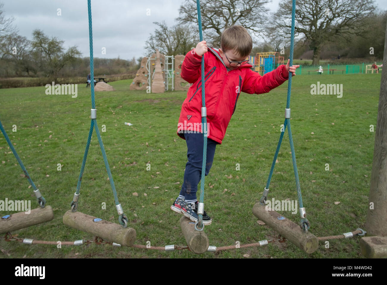 A young boy playing on a climbing frame in an outdoor park. Stock Photo