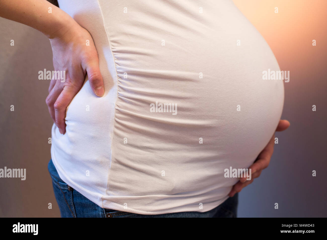 A heavily pregnant woman holding her back and her tummy Stock Photo
