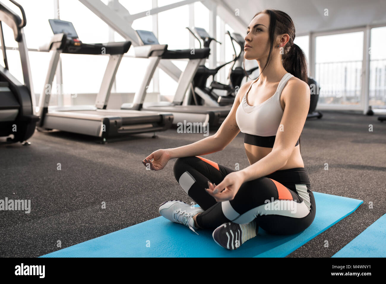 Full length portrait of fit young woman sitting on mat meditating ...