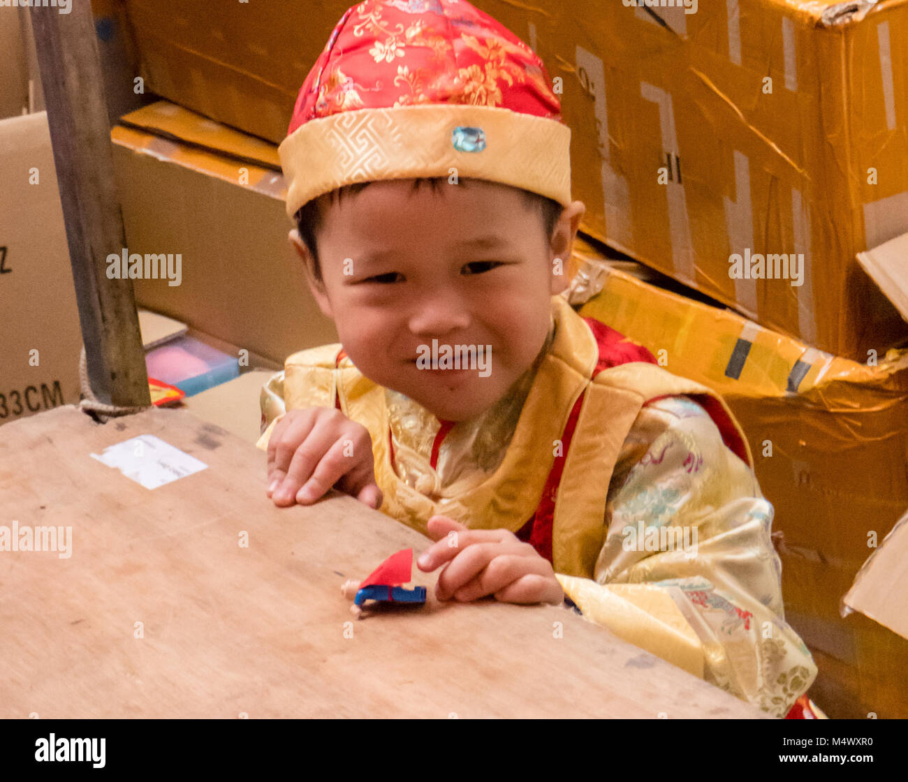 . Chinese New Year celebration in Chinatown, London,  Large crowds flock to Chinatown for the celebration, said to be the largest outside China,A little boy in traditional outfit helps on his parents stall Credit: Ian Davidson/Alamy Live News Stock Photo