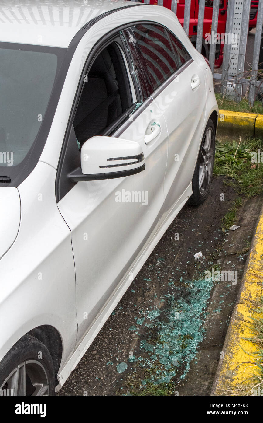 A vehicle broken into, damaged and items stolen in Manchester city centre car park with window glass smashed on pavement Stock Photo