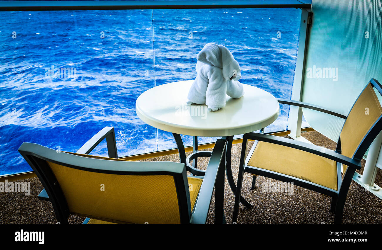 Towel shaped into the form of a dog sitting on a table on the balcony of a cruise ship cabin facing the ocean. Stock Photo