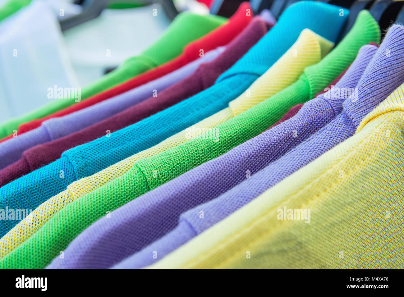 Cotton Polo Shirts of Various Colors Blue Yellow Red Purple Green White Hanging on Hangers on Rack in Clothing Store. Sales Retail Consumerism Fashion Stock Photo