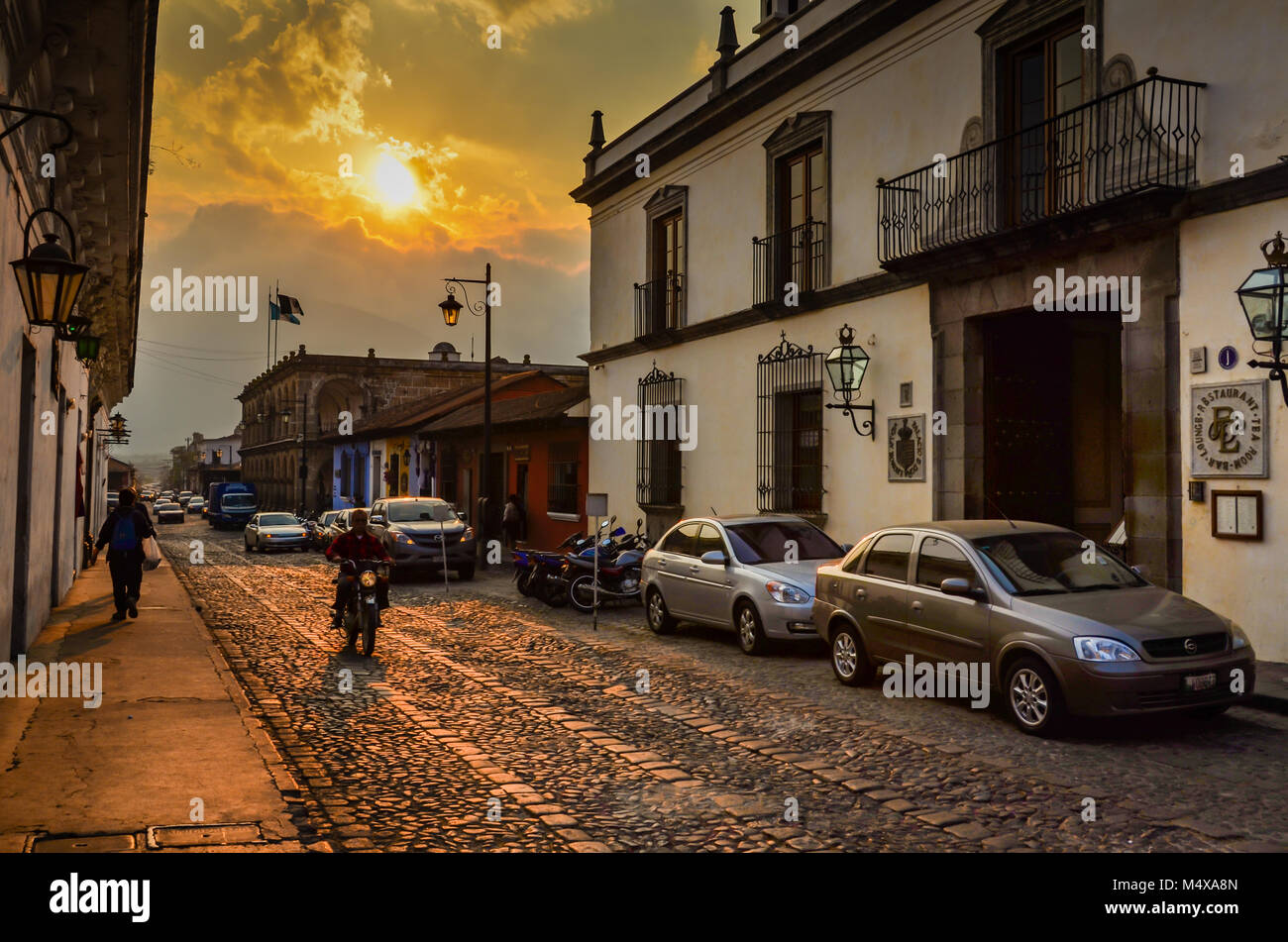 Setting sun casts golden glow on cobblestone street in old world Antigua. Stock Photo