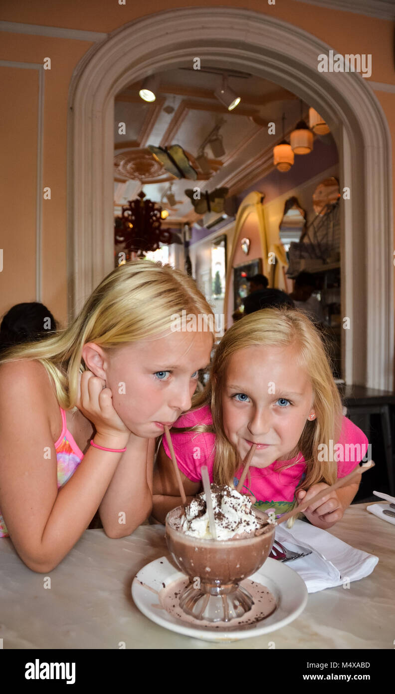 Vertical image of two blonde and blue eyed girls sip a Frozen Hot Chocolate dessert. Stock Photo