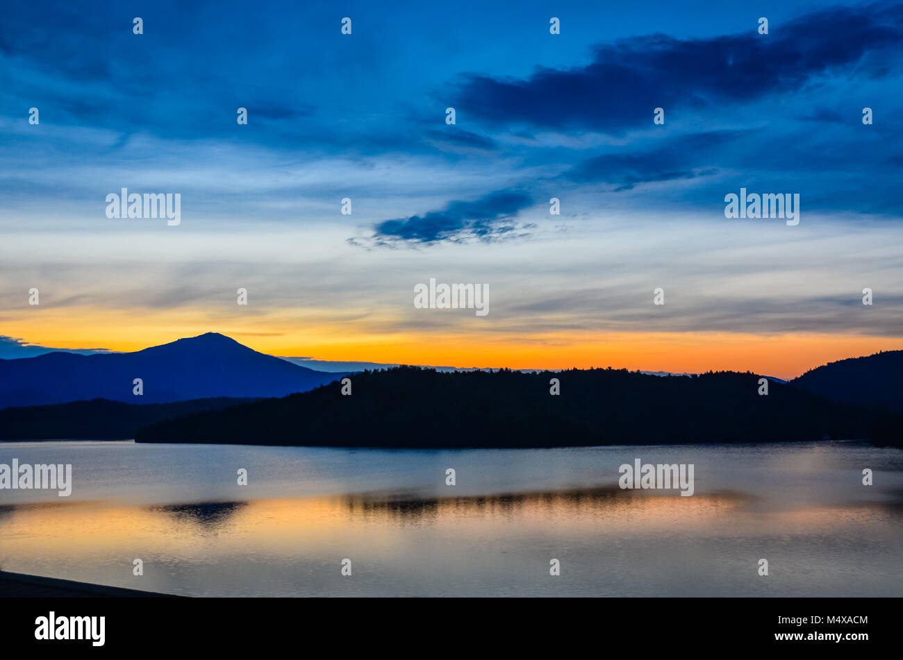 Glow of sun setting behind the Adirondack Mountains reflected on Lake Placid in Upstate New York. Stock Photo