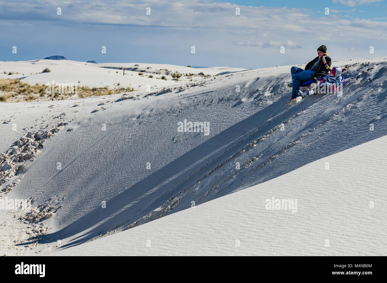 Sledding on the beautiful soft gypsum sand at White Sands National Monument is a popular activity and great fun for children and adults alike. Stock Photo