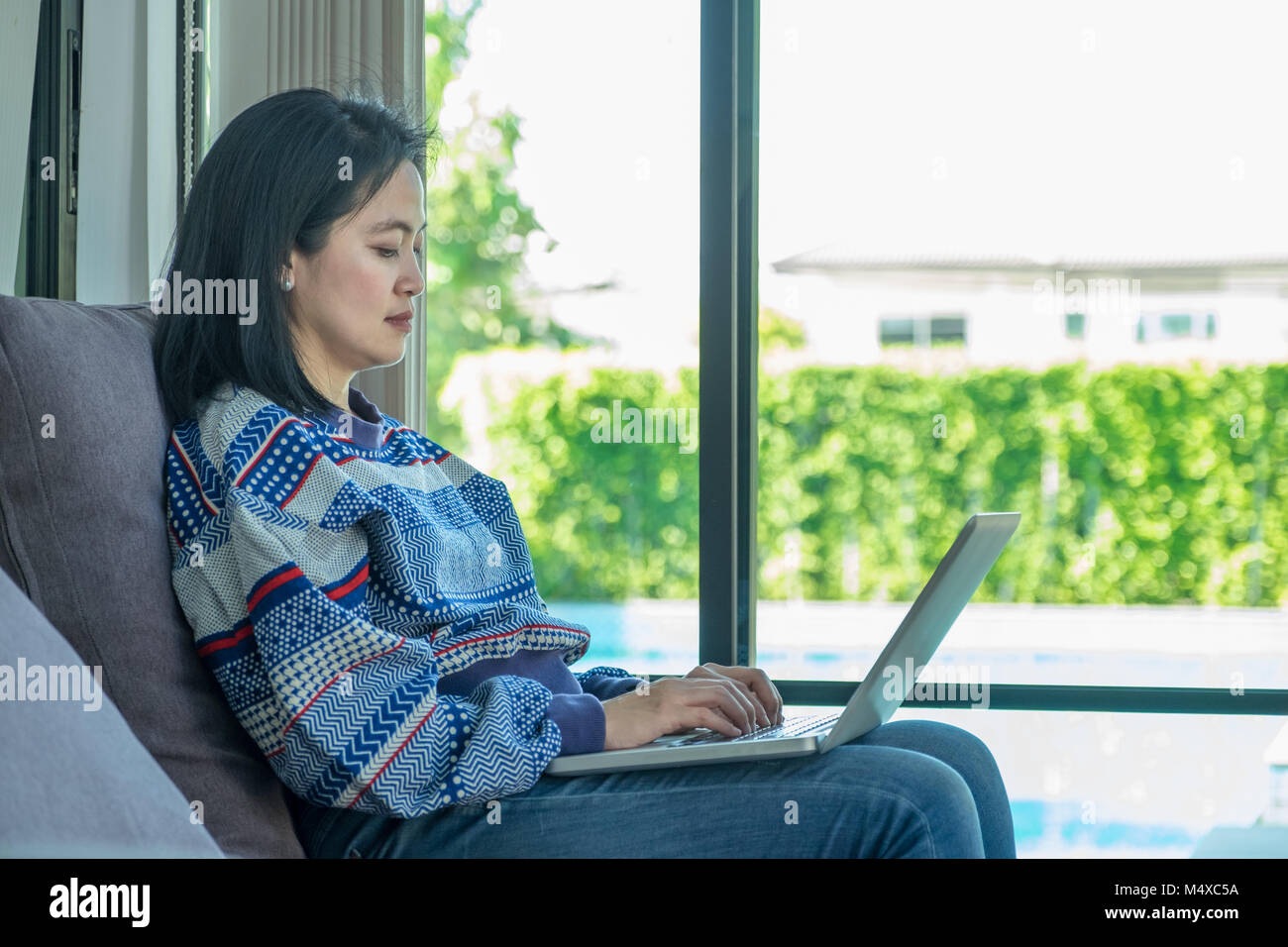 freelance woman working on laptop computer sitting on sofa at home ...