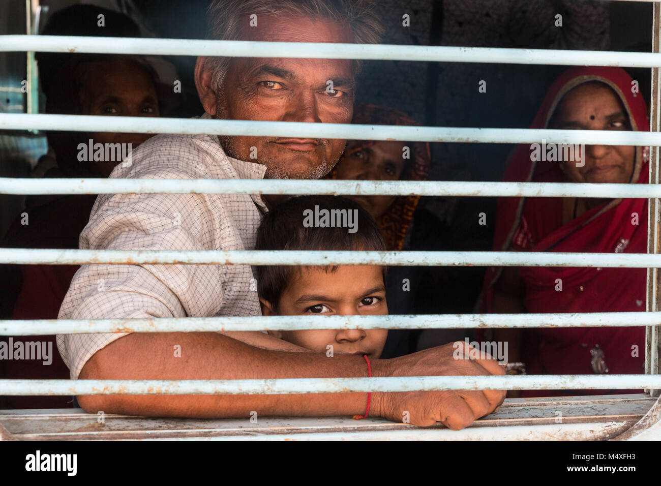 Father and son in an overcrowded indian train, looking proud out of the window, happy to have got a seat. Stock Photo