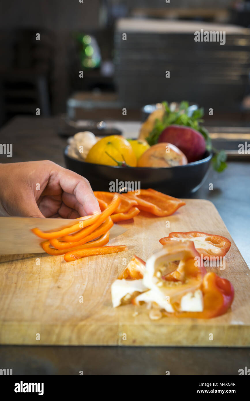 Chef cutting red bell pepper on wooden broad Stock Photo