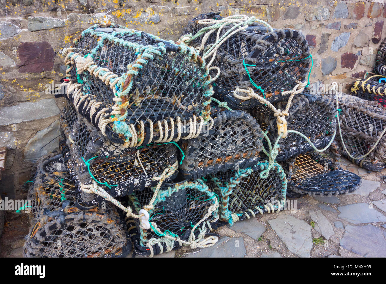 Lobster pots stacked against the harbour wall in Lynmouth Devon UK Stock Photo