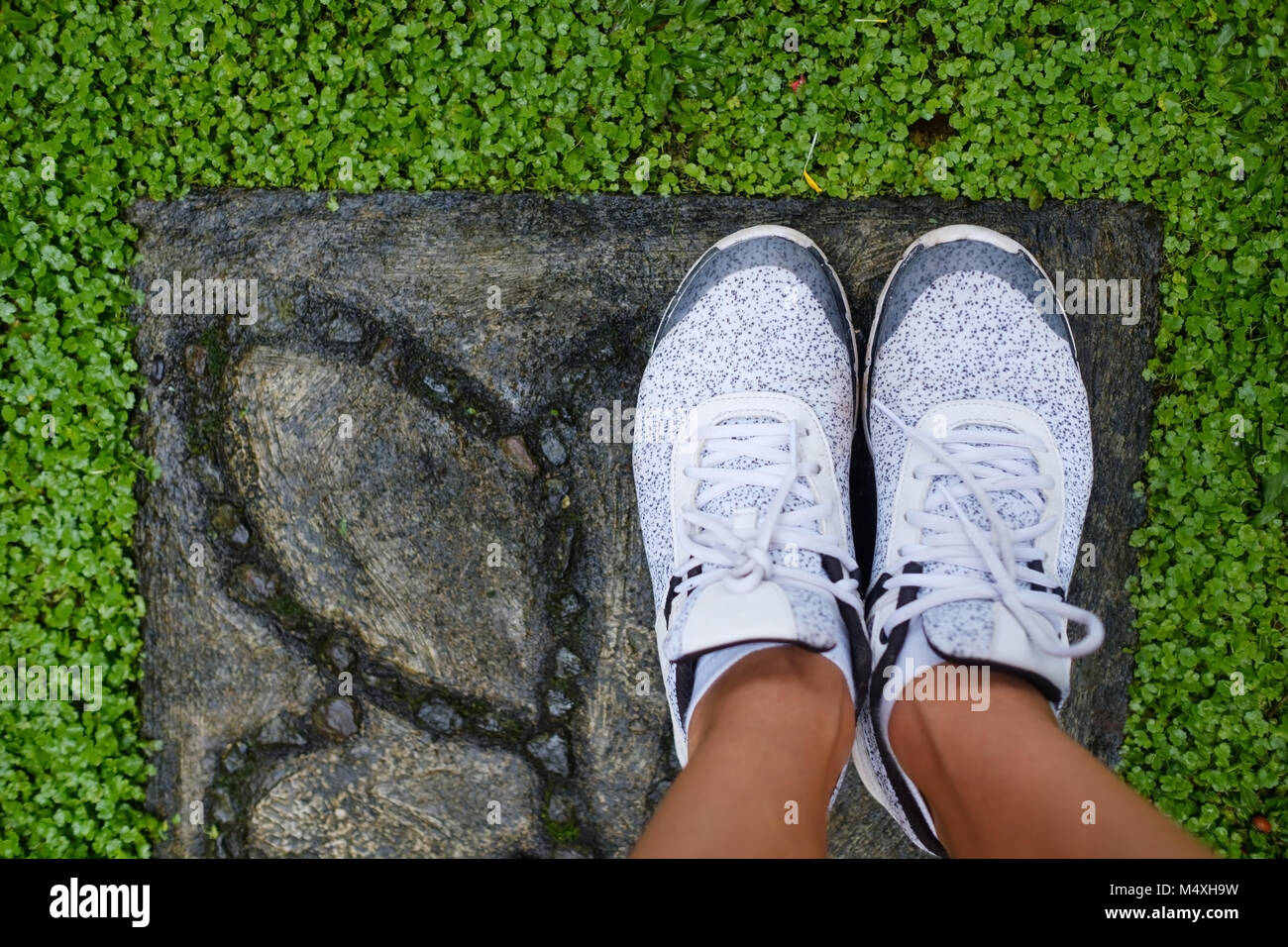 Girl standing in white shoes on green grass Stock Photo - Alamy