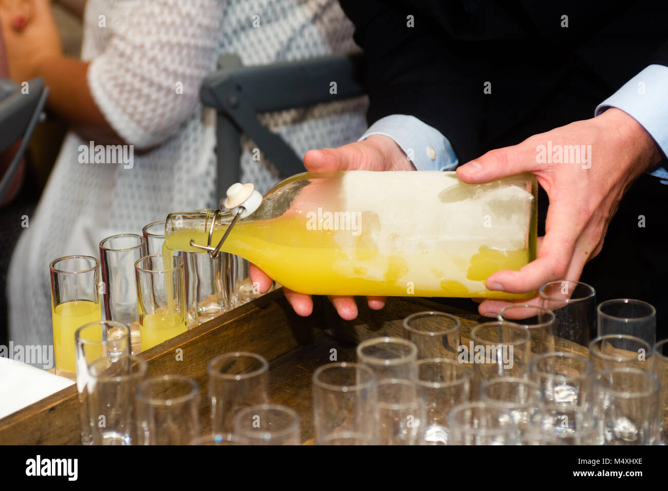 https://c8.alamy.com/comp/M4XHXE/close-up-of-a-waiter-serving-limoncello-in-glasses-at-a-party-M4XHXE.jpg