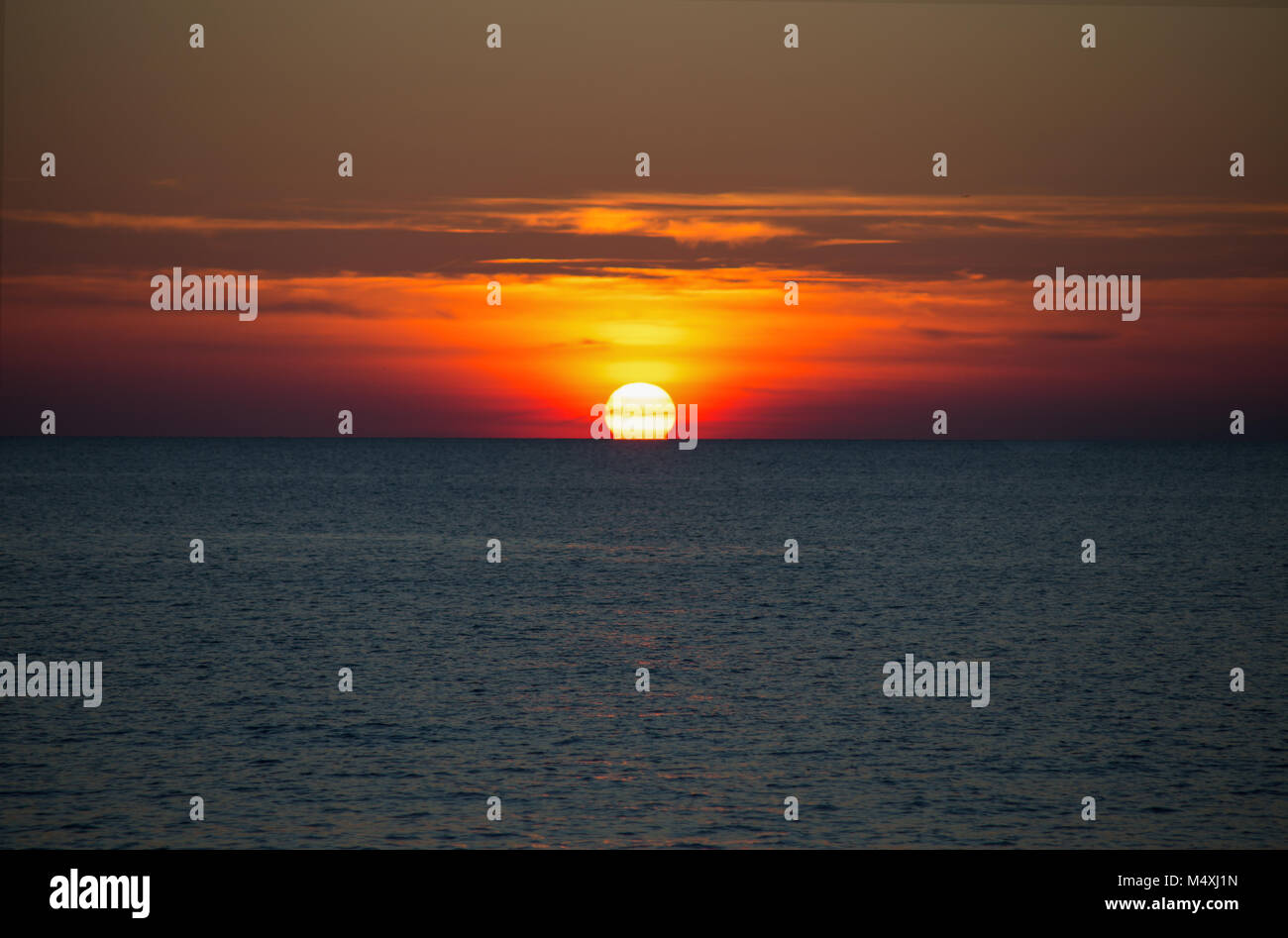 A beautiful sun setting on the horizon on the sea Stock Photo