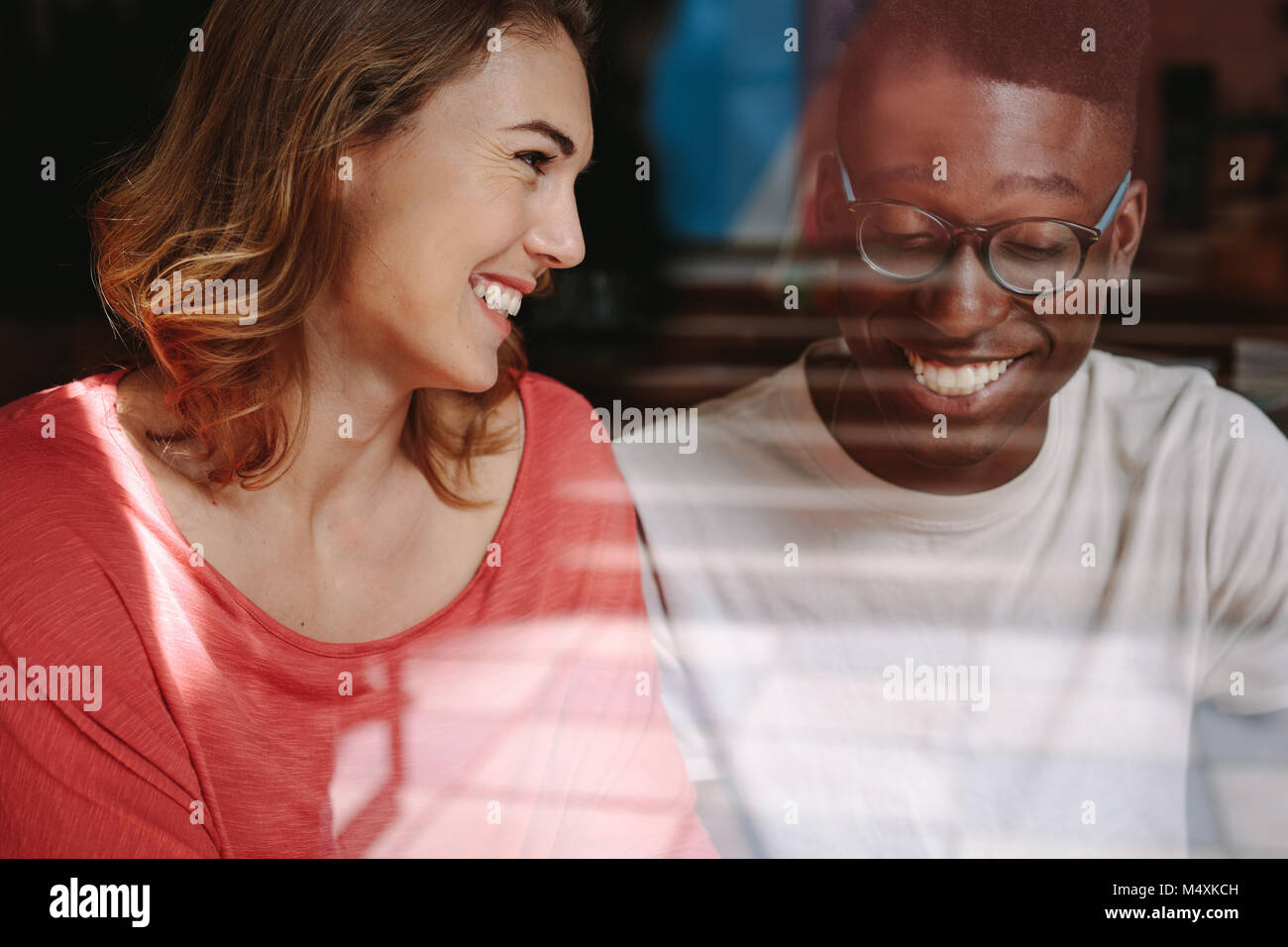 Smiling woman looking at her friend at a coffee shop. Friends sitting at a coffee shop and talking. Stock Photo