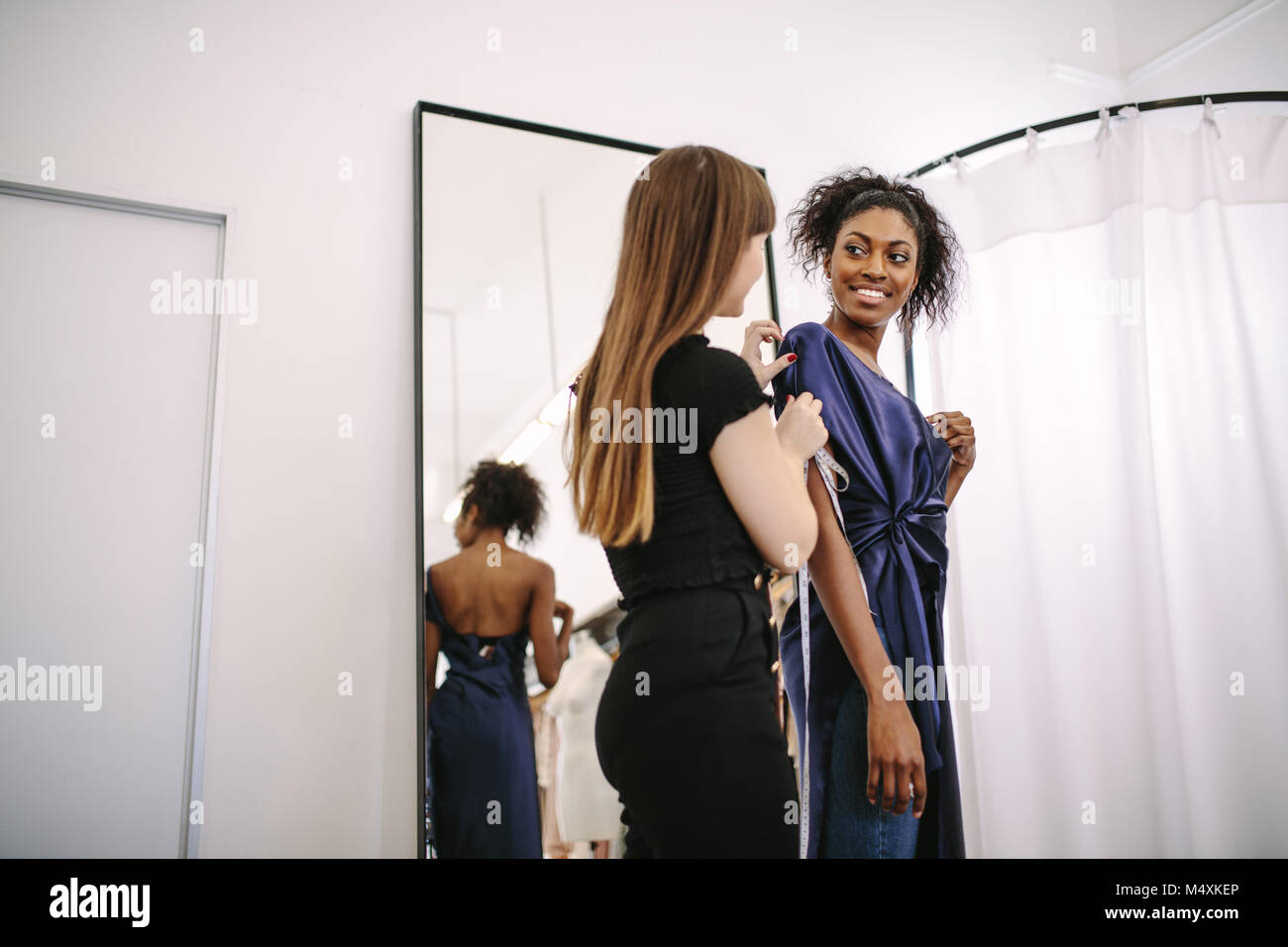 Fashion designer trying new designer clothes on a model. Woman entrepreneur in her cloth shop designing new clothes. Stock Photo