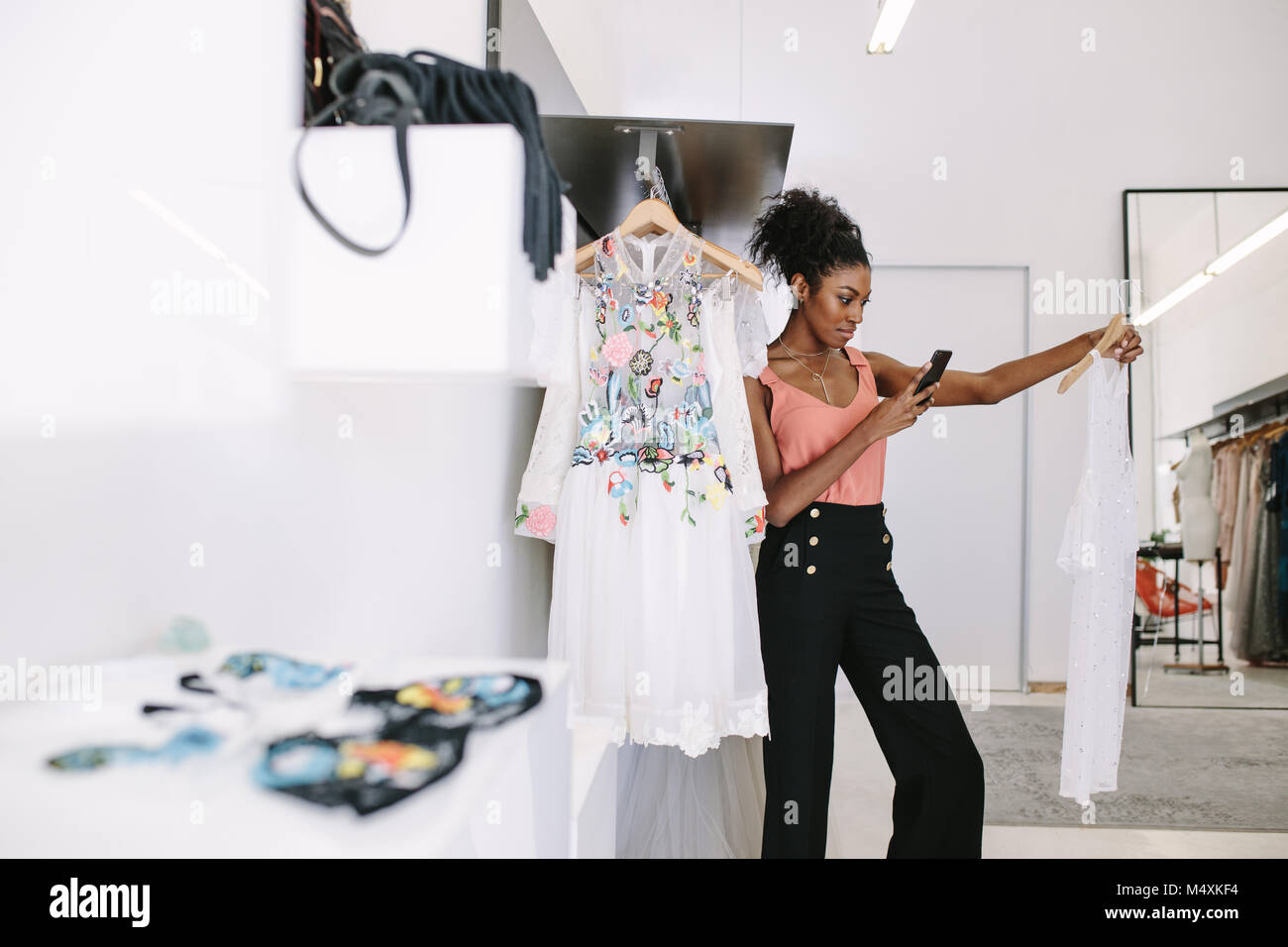 Fashion designer taking photograph of a designer dresses in her fashion studio. Customer taking photograph of dress in a fashion clothes shop. Stock Photo