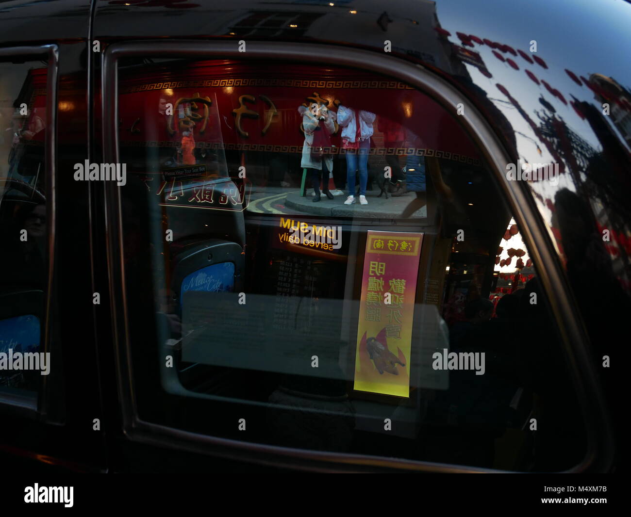 Banners, restaurant lights and tourists reflected in a London Black Cab during Chinese New Year 2018. Stock Photo