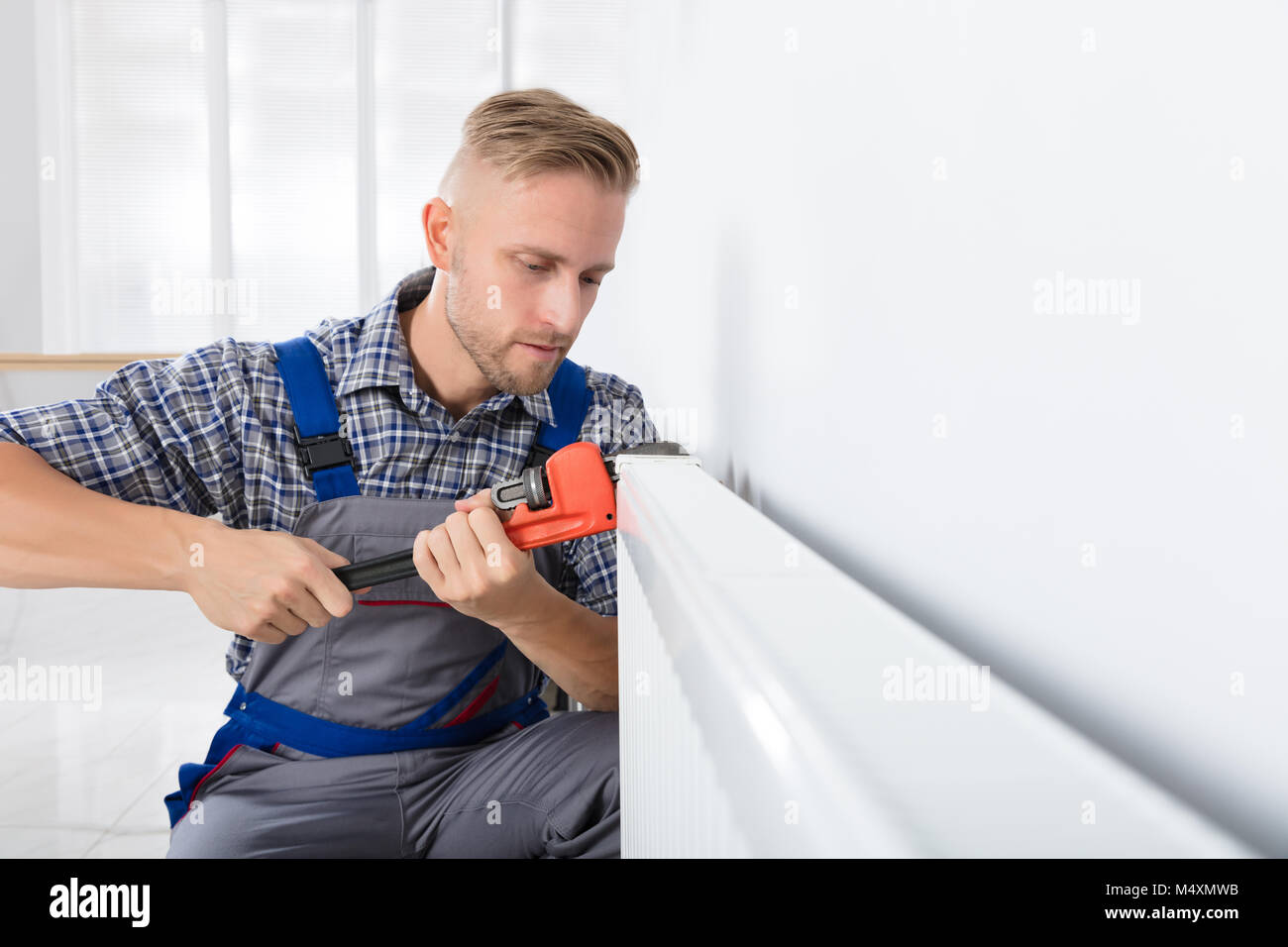Close-up Of Male Plumber Fixing Thermostat Using Wrench At Home Stock Photo