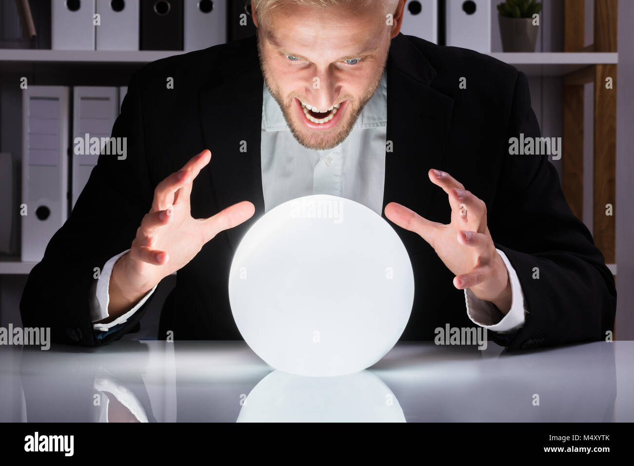 Young Businessman Looking Into The Future In A Crystal Ball In Office Stock Photo