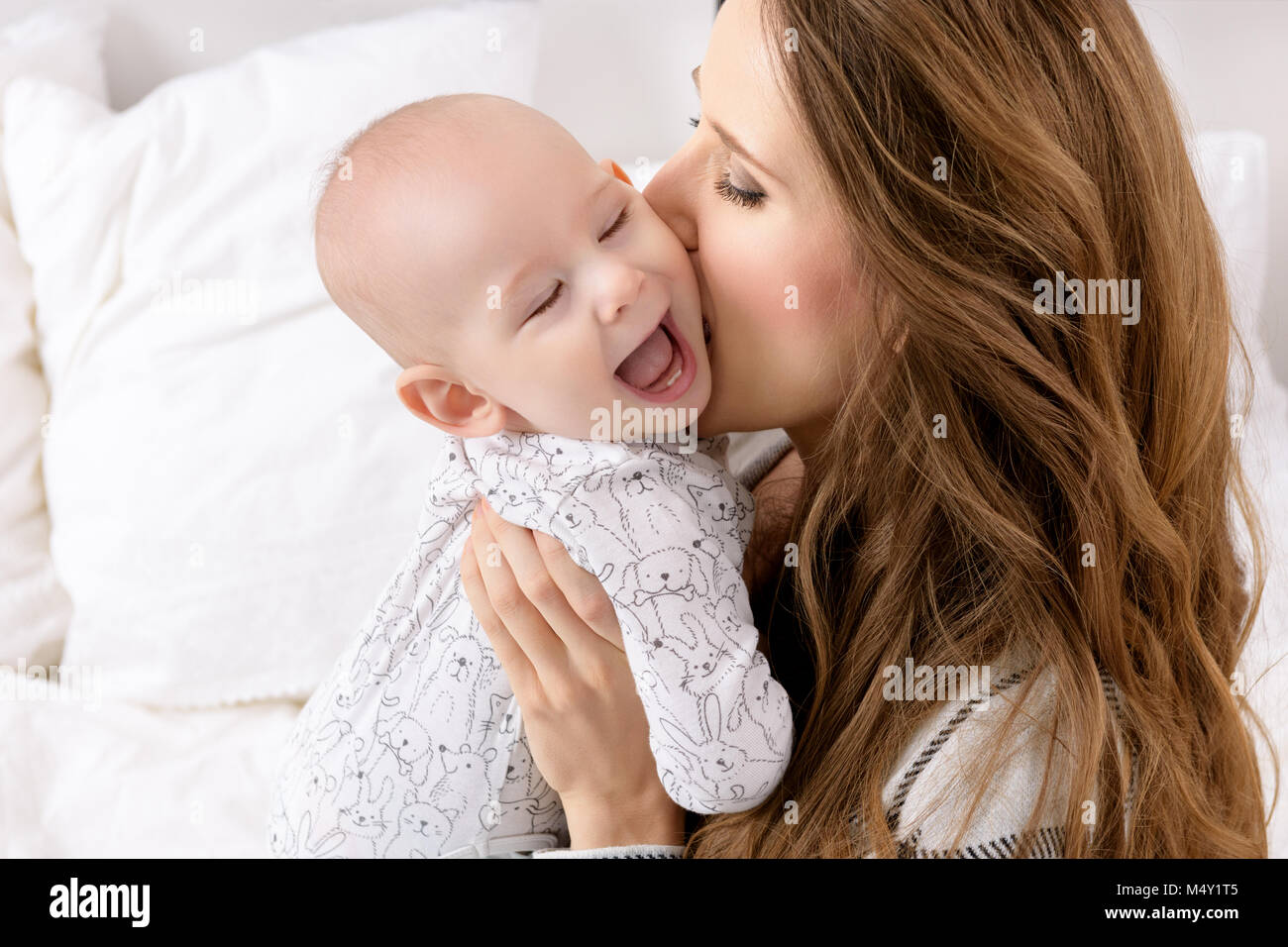 Happy mother kissing her adorable baby son. Happy family. Mother and newborn child playing in nursery portrait. Stock Photo