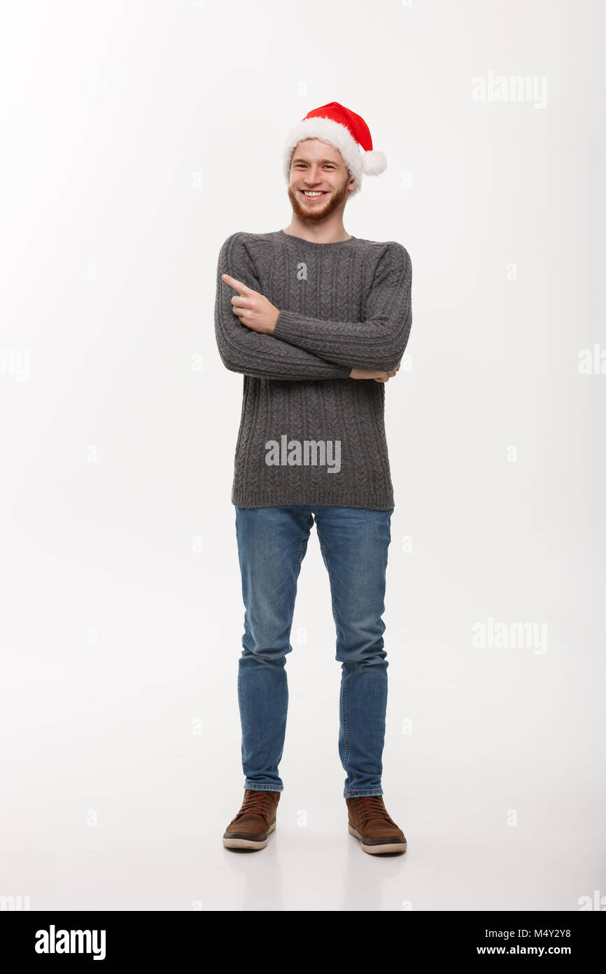 Holiday Concept - Young beard man in sweater enjoy playing and pointing finger onside with copyspace. Stock Photo
