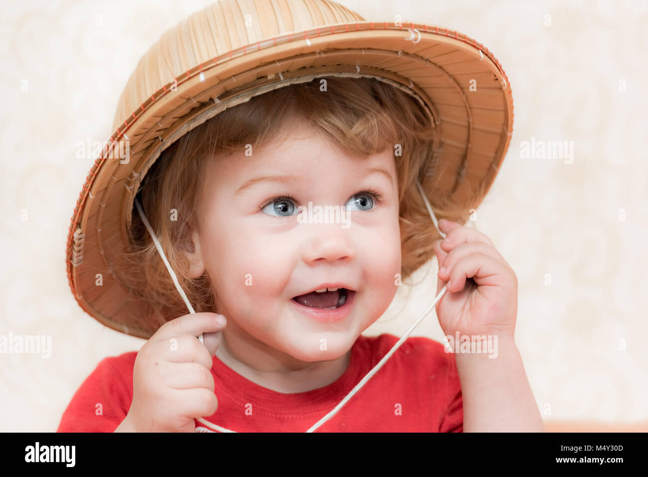 Blond curly-haired child straw hat Stock Photo