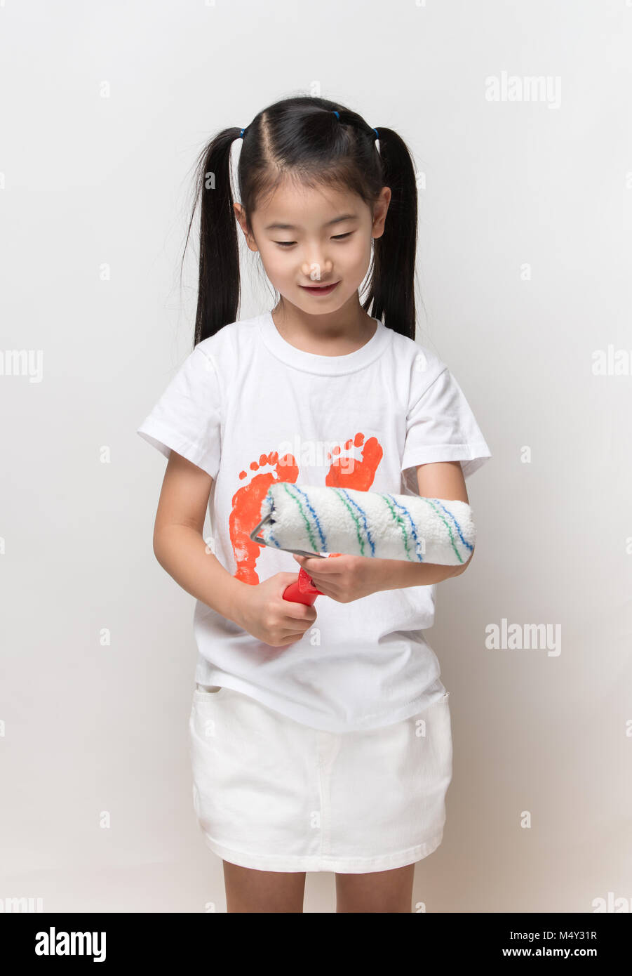Cute asian girl holding paint roller Stock Photo