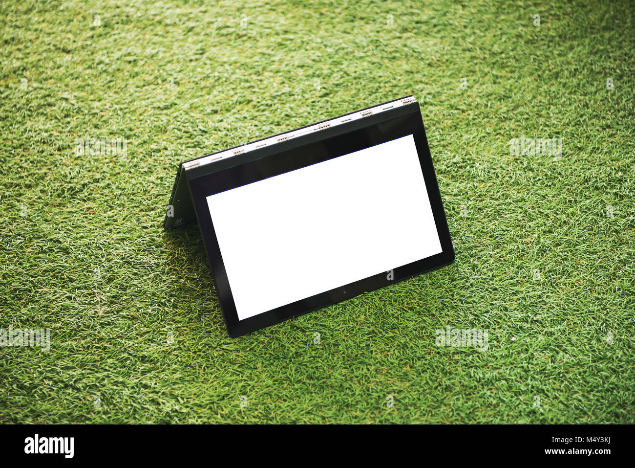 Laptop with blank white screen on the green grass Stock Photo