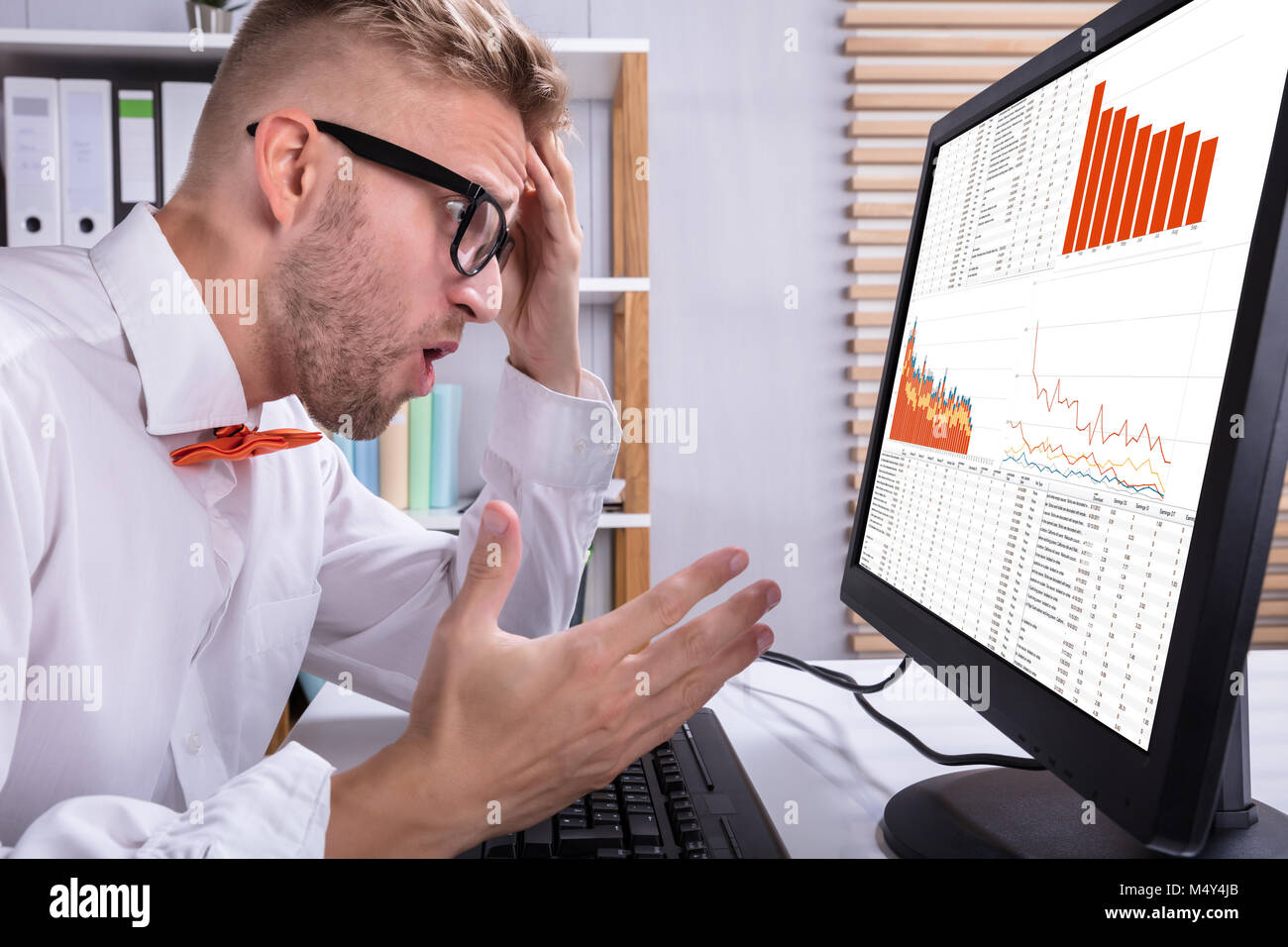 Worried Businessman Looking At Graph On Computer In Office Stock Photo