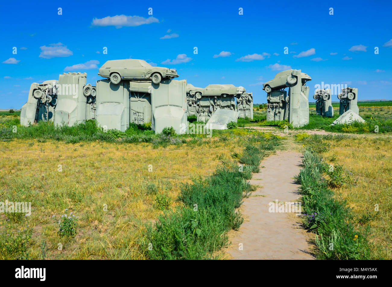 Outdoor sculpture of painted gray cars, arranged to look like Stonehenge, in a Nebraska field. This is a popular roadside attraction in the middle of  Stock Photo