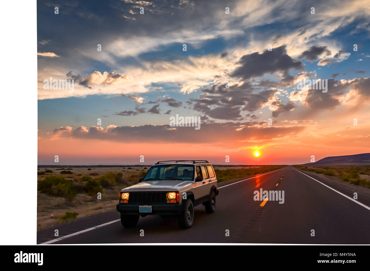 Sunset on Nevada highway, casting a glow on an SUV riding into the desert. Stock Photo