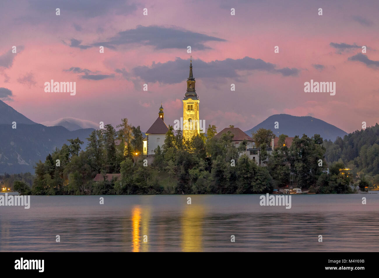 Landscape scene Lake Bled with St Mary's church on island and mountains in backdrop under pink stormy sky, Slovenia, Europe Stock Photo