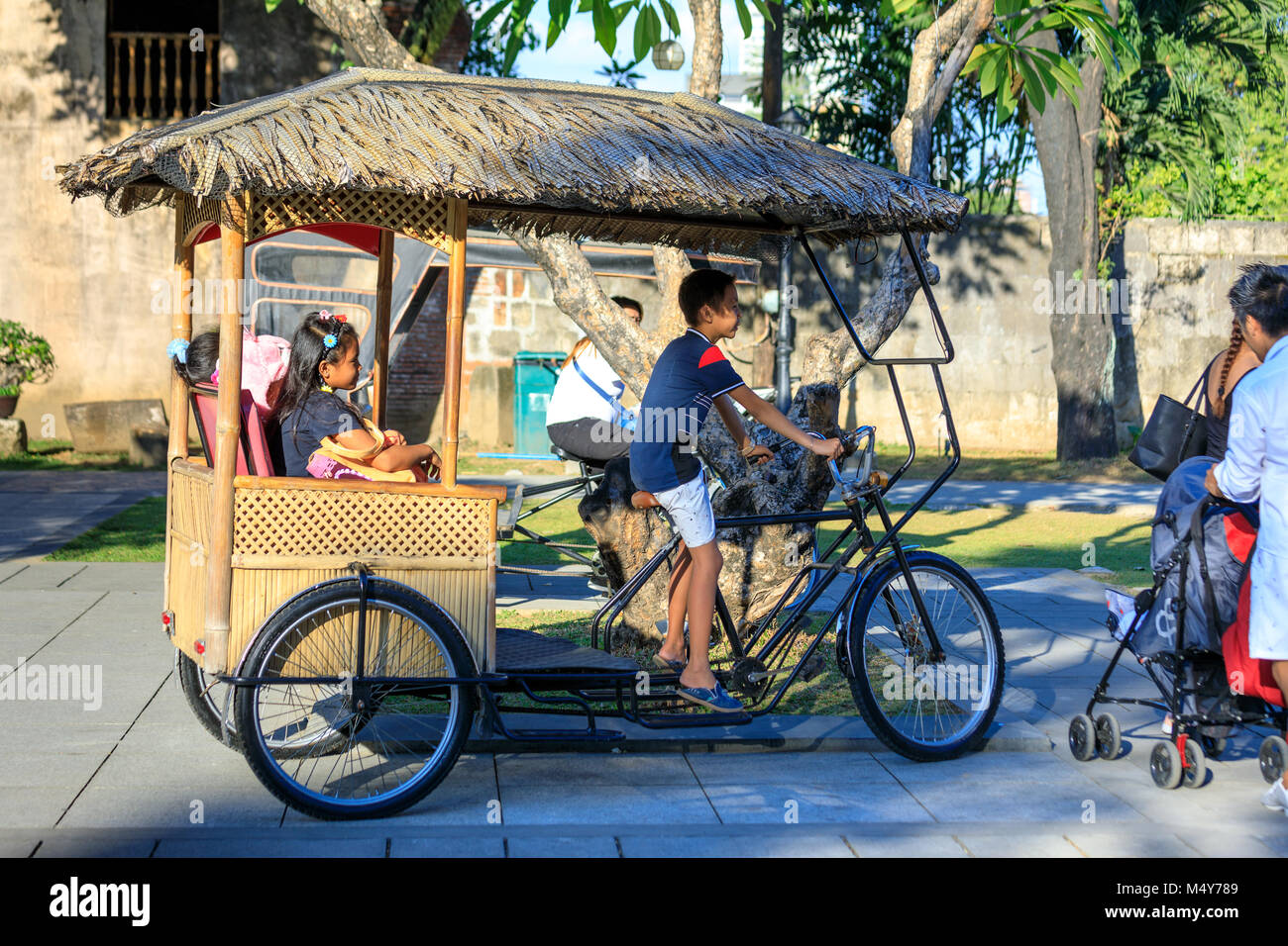Manila, Philippines - Feb 17, 2018 : Tourists ride on Philippines traditional tricycle at Fort Santiago garden in Intramuros district Stock Photo