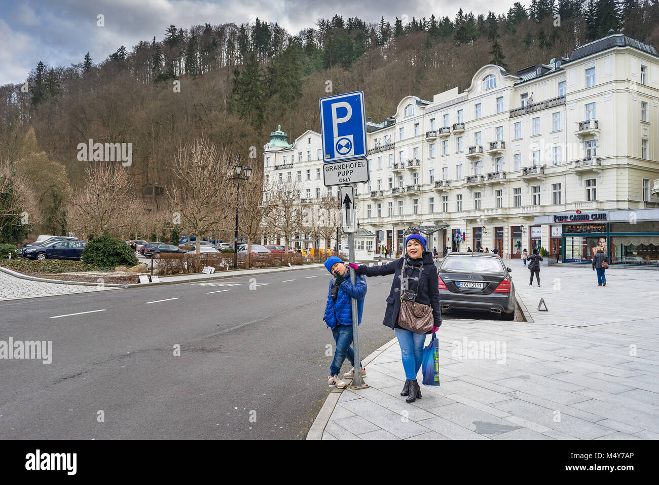 PRAGUE, CZECH REPUBLIC - MARCH 4, 2016: Asian boy and mom acting for still photo in front of Grandhotel Pupp on Karlovy Vary, Czech Republic. Stock Photo