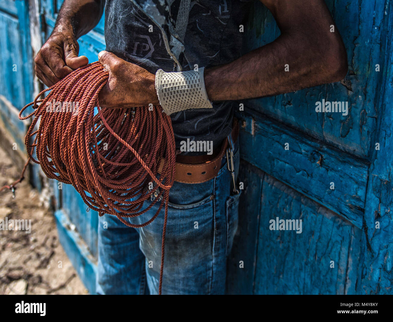 Moroccan fisherman holding a colourful orange red rope and standing ...