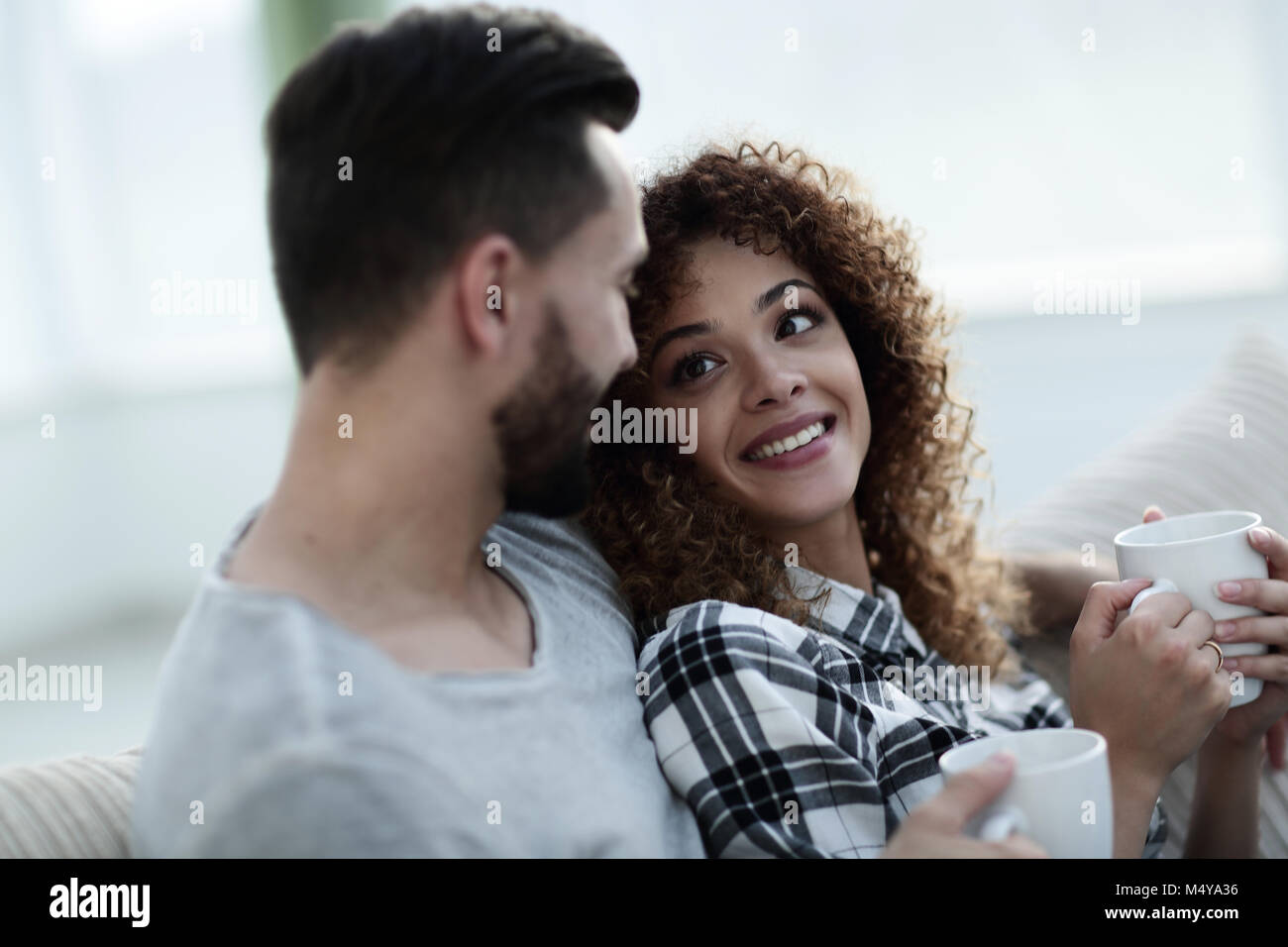 loving couple sitting on a sofa in the living room Stock Photo - Alamy