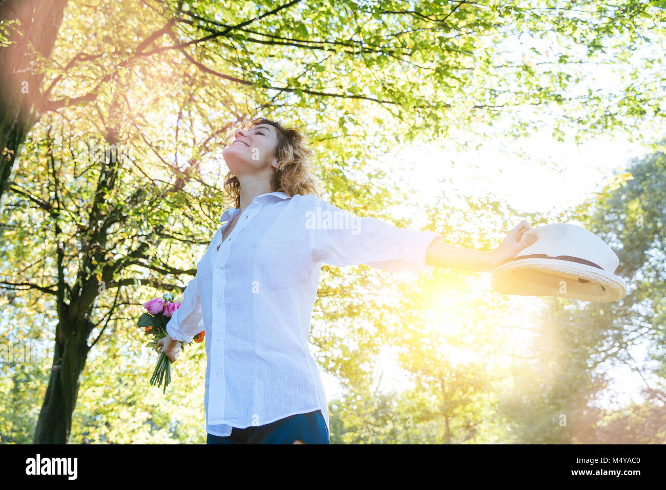 Enjoying the nature. Young woman arms raised enjoying the fresh air in green forest. Stock Photo