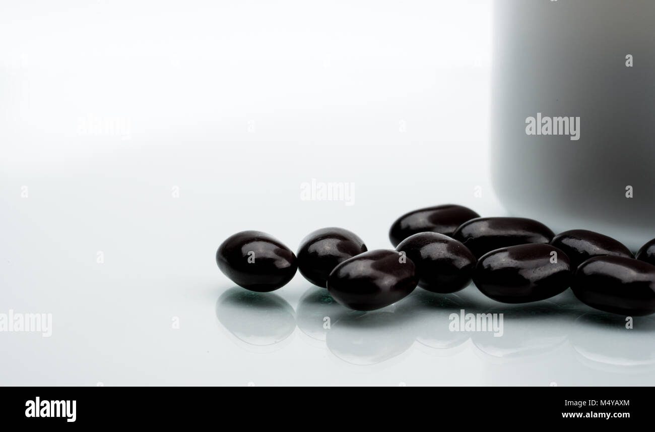 Black tablet pills on a white background. Vitamins and minerals tablets for pregnant women. Ferrous fumarate anemia treatment tablets pills. Stock Photo
