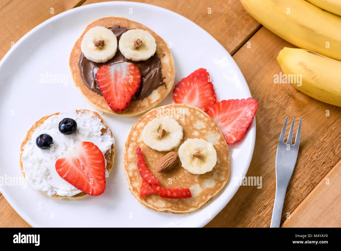 Pancakes With Funny Faces Decorated For Kids. Healthy Fruit Pancakes For Kids Meal Stock Photo