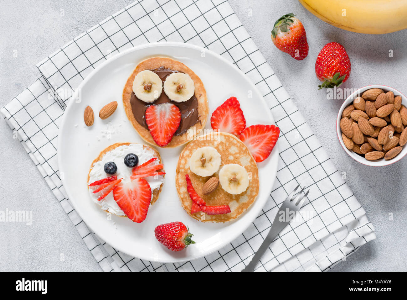 Funny pancakes with animal faces for kids on white plate. Top view Stock Photo