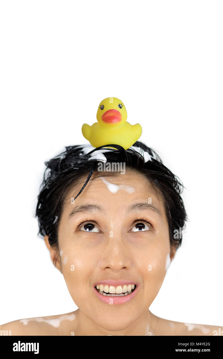 Yellow duck are on the head of a asian woman who is washing her hair isolated on white background. Stock Photo
