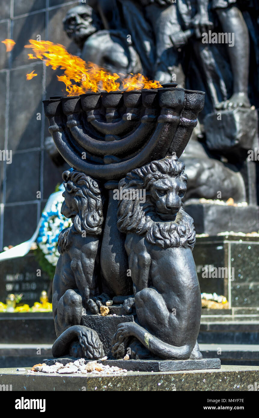 Menorah with burning flame in front of the Warsaw Ghetto Heroes Monument - Warsaw, Poland. Stock Photo